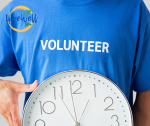 picture showing person holding a clock in a blue t shirt with the words volunteer across it
